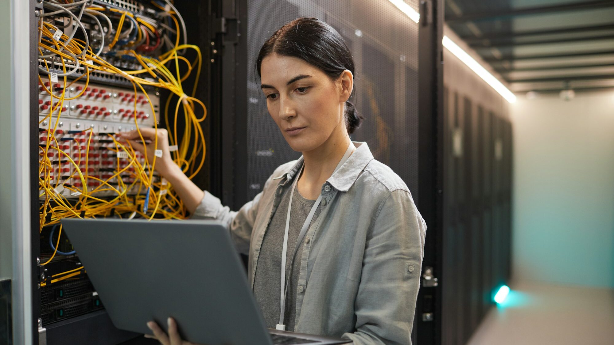 Female Network Technician Inspecting Servers in Data Center